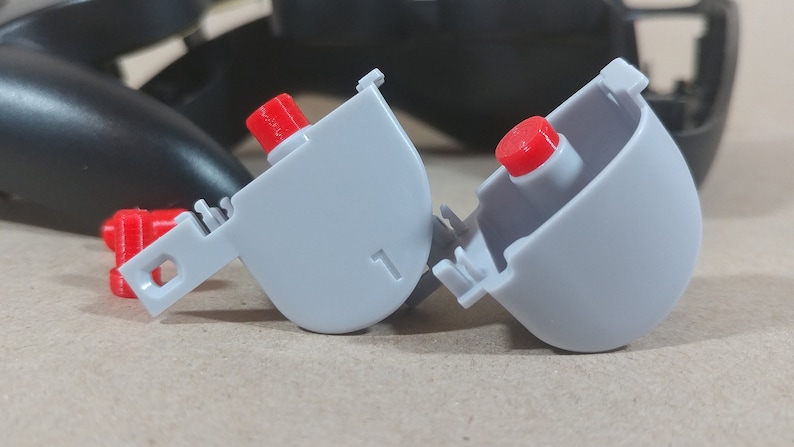 May include: Two gray plastic button covers with red buttons. The covers have a number "1" printed on them.