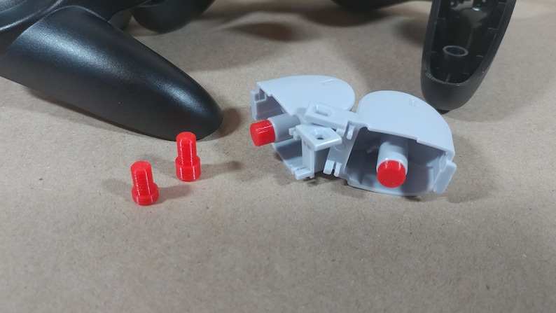 May include: A disassembled video game controller with three red plastic buttons and a gray plastic housing.