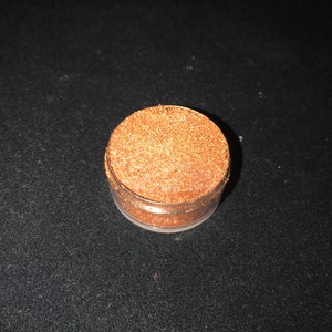 May include: A small round jar filled with fine gold glitter.