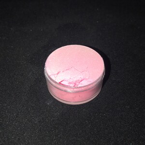 May include: A small round container filled with pink iridescent glitter.