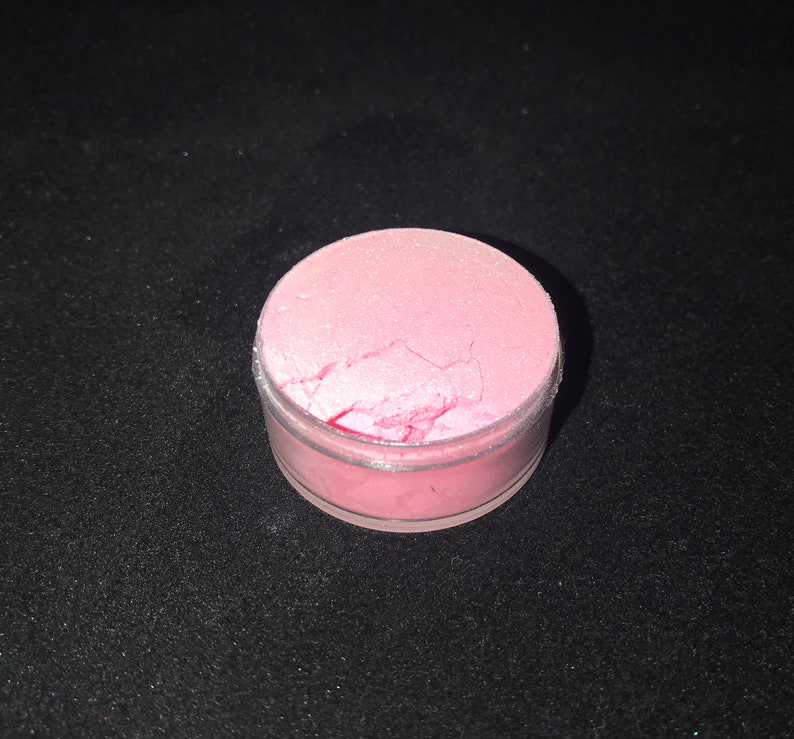 May include: A small round container filled with pink iridescent glitter.