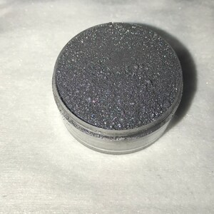 May include: A small round container filled with silver glitter.