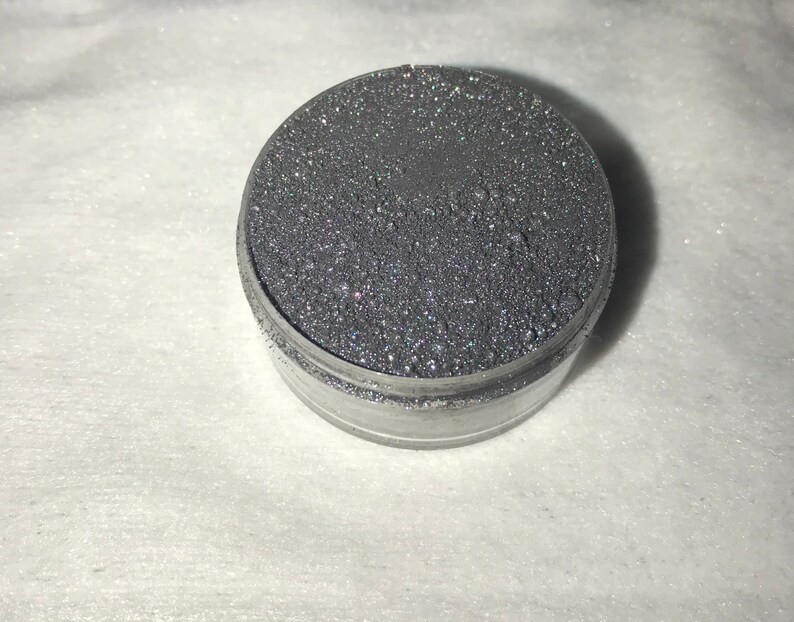 May include: A small round container filled with silver glitter.