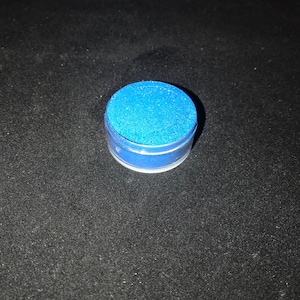 May include: A small round container of blue glitter.