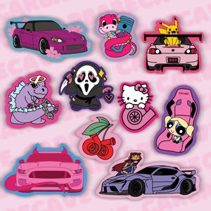 May include: A set of ten colorful stickers featuring various cartoon characters and cars. The stickers include a pink car with a halo, a purple car with a pink flower, a pink car with a yellow Pikachu, a pink car with a pink and white Hello Kitty, a pink car with a pink and white  'Recaro' seat, a pink car with a pink and white cherry, a pink car with a pink and white  'Blossom' character, a pink car with a pink and white  'Ghostface' character, a pink car with a pink and white  'Starfire' character, and a pink car with a pink and white  'Tyrannosaurus Rex' character.