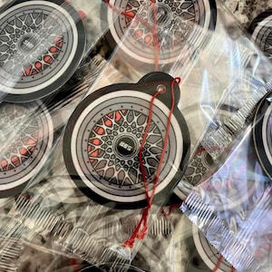 Puede incluir: Varios ambientadores para coche con un dise&ntilde;o de rueda con detalles grises, negros y rojos. Cada ambientador redondo tiene una cuerda roja para colgar. El dise&ntilde;o incluye el texto "BBS".