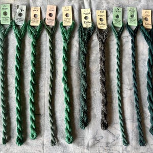 May include: Ten skeins of EdMar rayon embroidery thread in various shades of green and grey. Each skein features a paper tag with the brand name, color number, name, and length in yards and meters, including 16 Yds, 10.5 Yds, and 20.7 Yds.