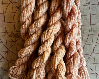 May include: Five skeins of peach-colored yarn, twisted together, with frayed ends.