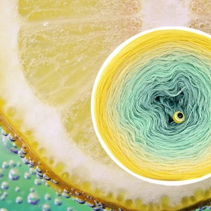 May include: A close-up of a lemon slice in a glass of sparkling water. The lemon is yellow and the water is green. The image is a color palette for a yarn gradient, with the colors labeled in Polish: "Intensywny Ż&oacute;łty", "Wanilia", "Jasna Pistacja", "Mieta", and "Patyna".
