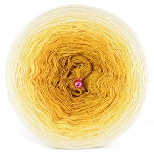 Può includere: Un gomitolo di filato ombré giallo e bianco con un ciondolo a campana rosa.