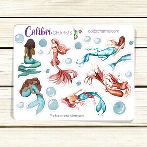 May include: A sheet of stickers featuring watercolor illustrations of mermaids with different colored tails and hair. The stickers are on a white background with the text "Colibri CHARMS" and "colibricharms.com" at the top and "Enchantment Mermaids" at the bottom.