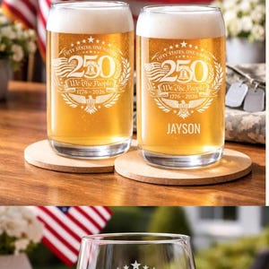 A collection of commemorative glassware featuring the text "250" and "We The People 1776-2026" for United States 250th Anniversary. The glasses are filled with various beverages, including whiskey, beer, and wine. The design includes the American flag and stars.