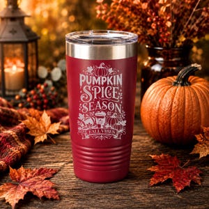 May include: A maroon stainless steel tumbler with a clear lid, featuring white laser-engraved text that reads PUMPKIN SPICE SEASON and FALL VIBES, accompanied by illustrations of pumpkins, a coffee cup, and a football surrounded by autumn leaves.