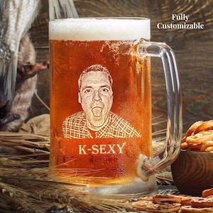 May include: A large, clear glass beer mug filled with amber-colored beer and a foamy head. The mug features a custom etched portrait of a person with their tongue out, and the text "K-SEXY" below. The words "Fully Customizable" are in the background.