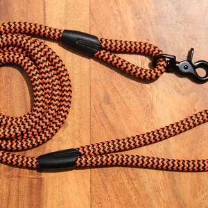 Könnte beinhalten: Orangefarbenes und schwarzes geflochtenes Hundehalsband mit einem schwarzen Metallclip und einem schwarzen Metallring.