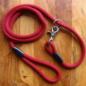 May include: Red rope dog leash with a black handle and a silver clip.