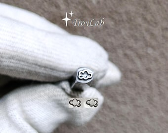 May include: A silver-colored metal stamping tool with a cloud-shaped tip. The tool features a square shaft and is held by a gloved hand. Below the tool, two small cloud-shaped impressions are visible. The text TroyLab is printed above the tool.