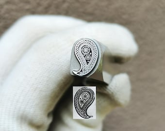 May include: A metal stamping tool featuring a paisley design on its face, with the brand name TroyLab printed above. The tool is shown with a clear black ink impression of the paisley pattern, which includes intricate floral and dot details.