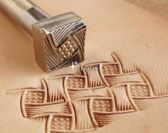 May include: A metal leather stamping tool with a square head featuring a geometric basketweave pattern and a textured handle. The tool is positioned above a piece of light tan leather that displays a stamped impression of the same design.