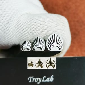 Peut inclure: Trois tampons métalliques avec un motif en forme d'éventail sont présentés. Les tampons sont de tailles différentes, avec un motif assorti de lignes courbes rayonnant d'un point central. Le texte "TroyLab" est visible sur une surface noire.