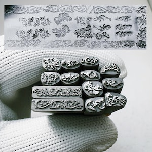 May include: A collection of metal stamps with various floral and ornamental designs. The stamps are in different shapes and sizes, with detailed patterns. A metal plate above displays similar designs.