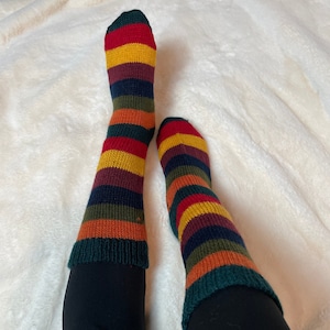 May include: A pair of striped socks in red, yellow, orange, green, and dark blue colours. The socks are knitted and have a thick texture.