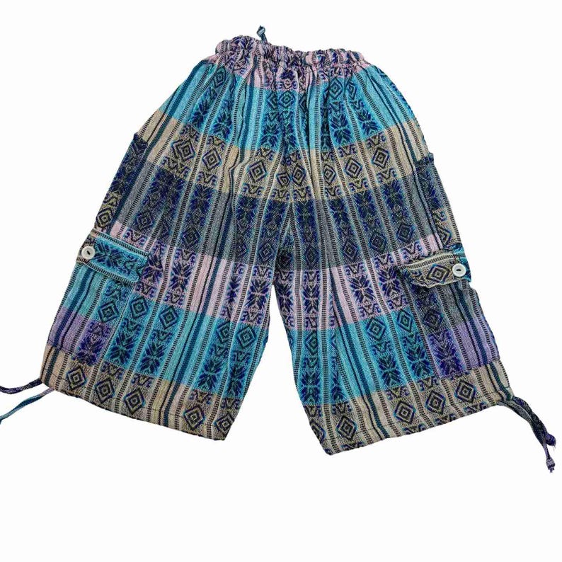 May include: Loose-fitting pants featuring a vibrant pattern of vertical stripes in shades of blue, purple, and beige. The garment includes an elasticized waistband with a drawstring, two side cargo pockets with white buttons, and adjustable ties at the hem.