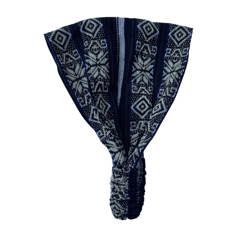 May include: A wide fabric headband featuring a dark navy blue and cream-colored woven pattern with geometric diamond and floral-like motifs. The accessory includes a gathered elastic section at the base to ensure a secure and flexible fit.