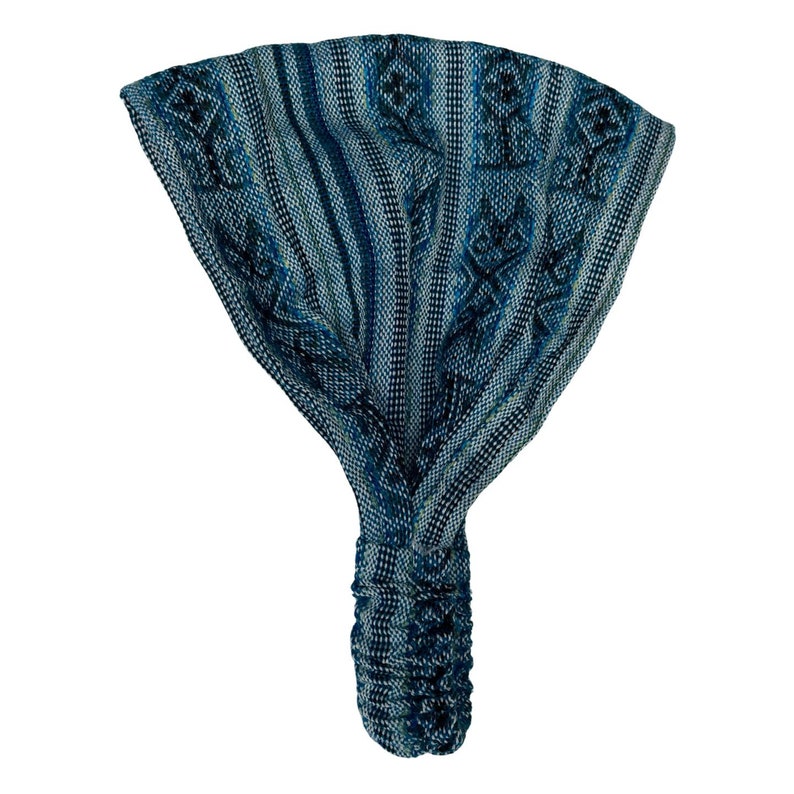 May include: A wide fabric headband featuring a woven pattern in shades of blue, teal, and black. The design includes vertical stripes and repeating geometric diamond motifs. The bottom section is gathered with an elastic band for a secure fit.