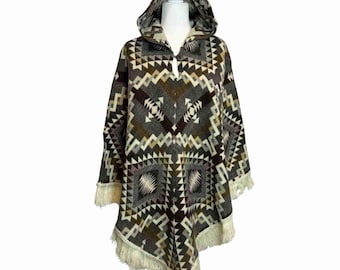 May include: A hooded poncho with a geometric pattern in shades of gray, brown, and cream. The poncho has a fringed hem and a button closure at the neckline. The design features triangles, squares, and diamond shapes.