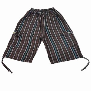 May include: Knee-length shorts featuring a vertical striped pattern in shades of brown, black, white, and blue. The garment includes an elastic waistband with a drawstring, two side cargo pockets with button closures, and adjustable ties at the hem.