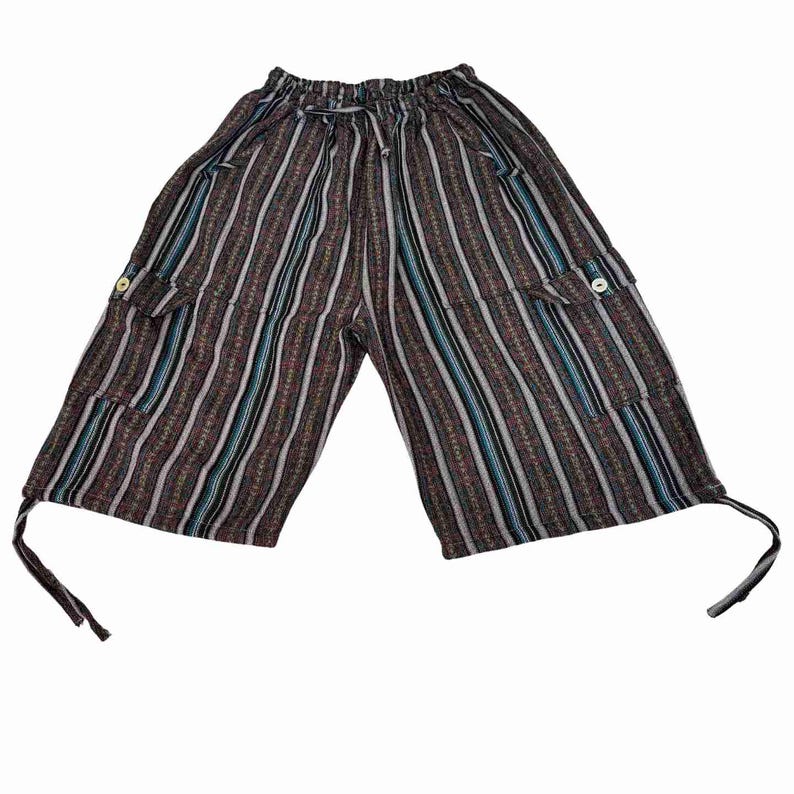 May include: Knee-length shorts featuring a vertical striped pattern in shades of brown, black, white, and blue. The garment includes an elastic waistband with a drawstring, two side cargo pockets with button closures, and adjustable ties at the hem.
