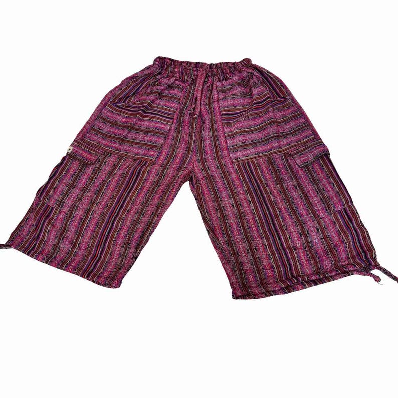 May include: Mid-length shorts featuring a vibrant magenta, purple, and black vertical striped pattern with intricate geometric details. These shorts include an elasticized waistband with a drawstring, two side cargo pockets, and adjustable ties at the leg hems.