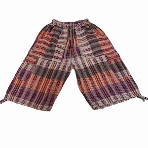 May include: Mid-calf length pants featuring a vibrant, multi-colored woven pattern in shades of orange, purple, and white. These pants include an elasticized waistband with a drawstring, side pockets, and adjustable tie-cords at the leg hems.