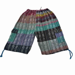 May include: Mid-length pants featuring a patchwork design with vertical stripes and geometric patterns in shades of teal, purple, black, and white. The pants include side cargo pockets, an elastic waistband, and blue drawstring ties at the hems.