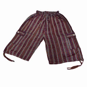 May include: Mid-length pants featuring a vertical striped pattern in shades of purple, red, orange, and white. The garment includes an elasticized waistband with a drawstring, two side cargo pockets with white buttons, and adjustable ties at the hem.