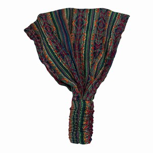 May include: A wide fabric headband featuring a multi-colored woven pattern with vertical stripes and geometric diamond shapes in shades of green, red, blue, and yellow. The accessory has a gathered elastic section at the base for a secure fit.