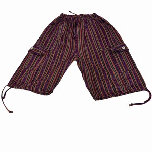 May include: Knee-length shorts featuring a vertical striped pattern in shades of purple, red, black, and yellow. The shorts have an elastic waistband with a drawstring, two side cargo pockets with white buttons, and adjustable drawstrings at the hems.