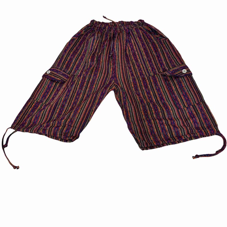 May include: Knee-length shorts featuring a vertical striped pattern in shades of purple, red, black, and yellow. The shorts have an elastic waistband with a drawstring, two side cargo pockets with white buttons, and adjustable drawstrings at the hems.