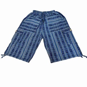May include: Blue and light blue patterned cropped pants featuring an elastic waistband with a drawstring, two side cargo pockets with light-colored buttons, and adjustable tie-string closures at the bottom of each leg opening.