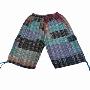 May include: Mid-length shorts featuring a patchwork design with various geometric and floral patterns in shades of teal, purple, black, and white. The shorts have an elastic waistband with a drawstring and adjustable ties at the leg openings.
