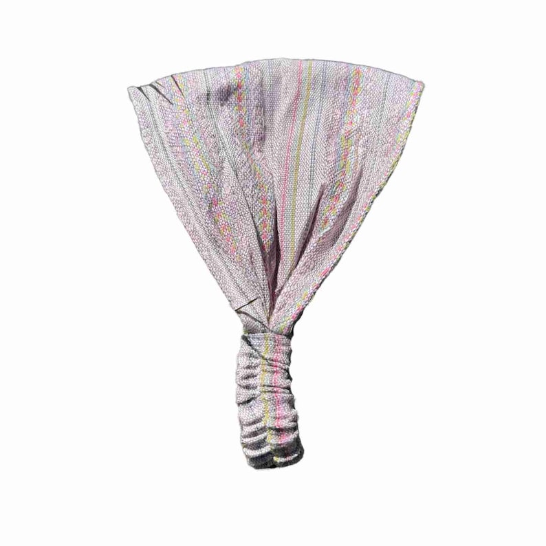 May include: A wide fabric headband featuring a light lavender base color with vertical stripes in shades of yellow, pink, and blue. The accessory has a gathered, elasticized section at the bottom to ensure a secure fit around the head.