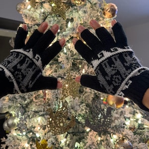 May include: A pair of black fingerless gloves with a white and gray geometric pattern. The gloves are made of a soft, knitted fabric.