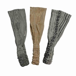 Op de afbeelding: Drie gepatroneerde haarbanden in grijs, beige en wit met zwarte accenten. De haarbanden zijn gemaakt van een zachte, rekbare stof en zijn perfect om haar uit je gezicht te houden.