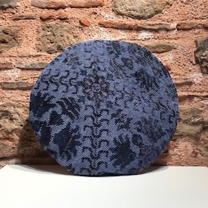 May include: A round blue and black patterned throw pillow with a woven texture.