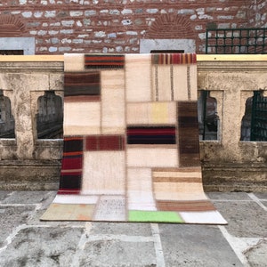 Può includere: Un tappeto patchwork con sfondo crema e motivi geometrici colorati. Il tappeto è realizzato con diversi tessuti e trame, creando un look unico ed eclettico.