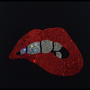 Op de afbeelding: Rode lippen met witte tanden van strass op een zwarte achtergrond.