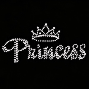 Pode incluir: Um design de transferência de strass com a palavra Princess em uma fonte cursiva, posicionada abaixo de um gráfico de coroa de cinco pontas. Todo o design é composto por strass circulares transparentes e reflexivos sobre um fundo preto.