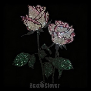 May include: A rhinestone applique featuring two roses with cream and deep red petals, accented by dark green leaves. The design is covered in shimmering crystals against a black background, with the text NextClover printed at the bottom.