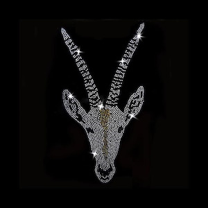 Può includere: Un design di testa di gazzella scintillante, tempestato di strass, su sfondo nero. La testa e le corna della gazzella sono delineate da numerosi piccoli strass riflettenti, creando un effetto abbagliante. Le corna sono lunghe e curve, e il design è simmetrico.